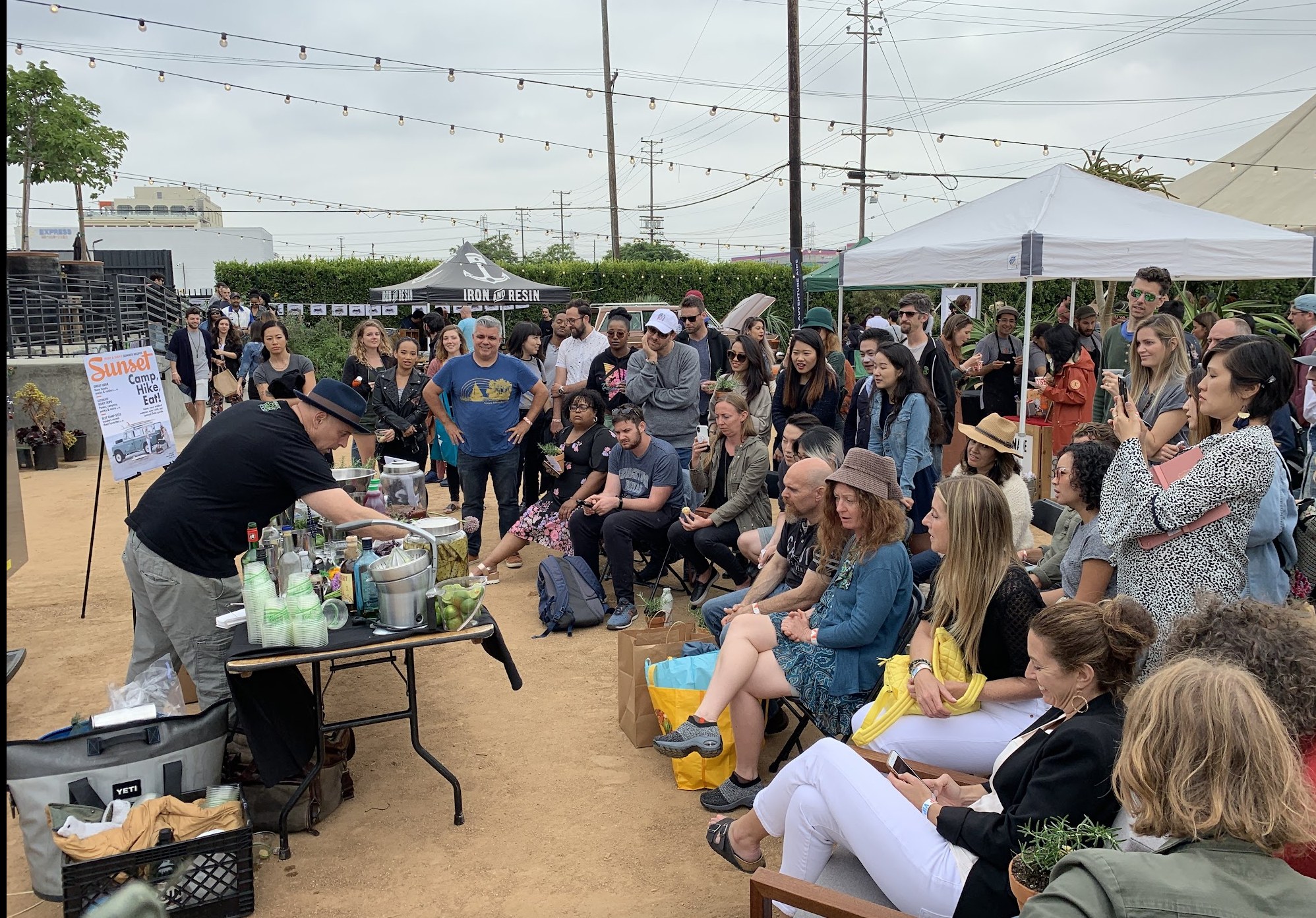 A crowd gathered for a live cocktail demo at a Sunset outdoor brand event